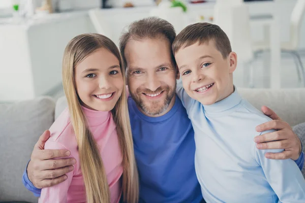 Photo of positive father embrace two pretty kids boy girl sit divan in house indoors — Stock Photo, Image