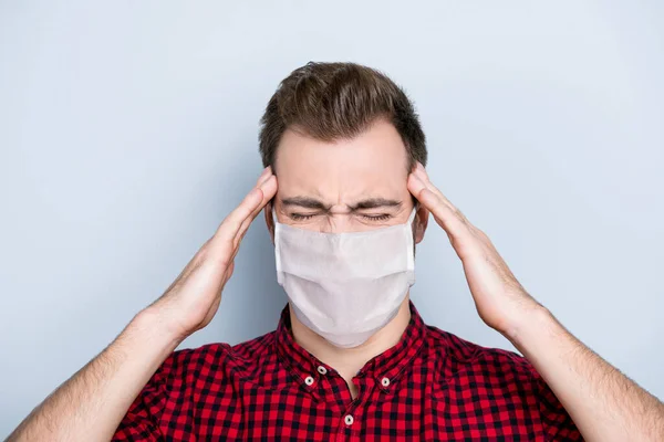 Concept of feeling the first symptoms of corona virus. Close up portrait of unhappy man suffering from throbbing pain in head wearing white face mask isolated on gray background — Stock Photo, Image