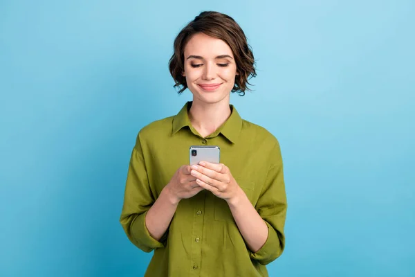美しいかわいい女性の短いヘアドアの手の写真電話を保持する画面の笑顔読み取りタイプ書き込み緑のシャツ隔離された青の色の背景を着用 — ストック写真