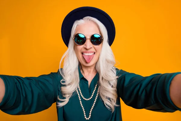Κοντινό πλάνο φωτογραφία του δροσερό τρελό λευκό μαλλιά γιαγιά κυρία κάνει selfies αισθάνονται νέοι κολλήσει γλώσσα έξω από το στόμα φορούν πράσινο πουκάμισο sun specs κολιέ πολυτελείας απομονωμένο κίτρινο φωτεινό χρώμα φόντο — Φωτογραφία Αρχείου