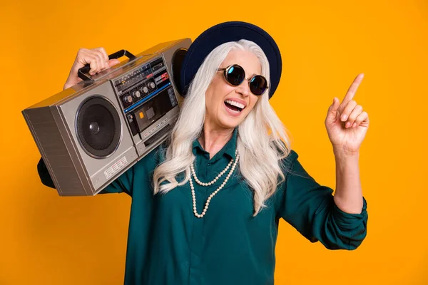 Foto de louco legal vovó senhora música amante sênior festa gravador ombro direto dedo vazio espaço desgaste verde camisa sol especificações colar retro cap isolado amarelo cor fundo — Fotografia de Stock