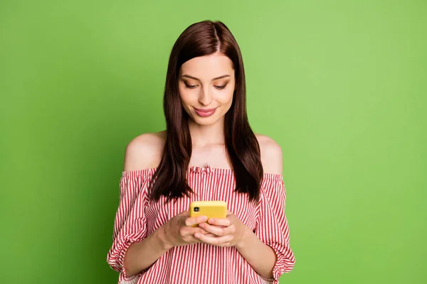 Foto van vrij charmante student meisje glimlach hold mobiele telefoon sms 'en vriend uitnodigen verjaardag partij dragen gestreepte witte rode blouse onbedekte schouders fel groene kleur achtergrond — Stockfoto