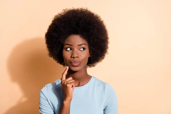 Foto retrato de mujer afroamericana pensando tocar la cara de la barbilla con un dedo aislado sobre fondo de color beige pastel —  Fotos de Stock