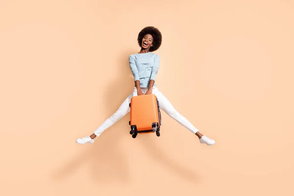 오렌지 수트를 입고 있는 아프리카계 미국인 여성이 파스텔 베이지 색 배경에 고립 된 입을 벌리고 뛰어 오르는 사진. — 스톡 사진