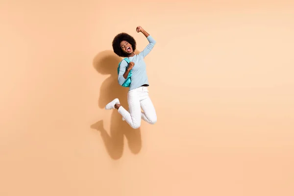 Foto ritratto della giovane donna afro-americana allegra che salta su celebrando la vittoria isolata su sfondo color beige pastello — Foto Stock