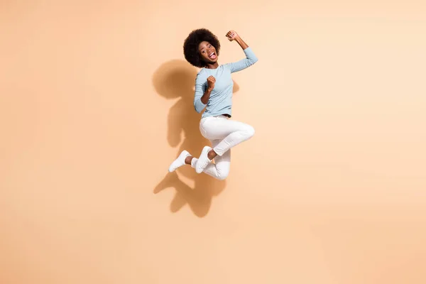 Foto portrét ohromený africký Američan dívka skákání do jásotu křičí izolované na pastelové béžové barevné pozadí — Stock fotografie