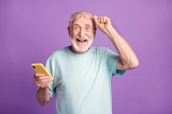 Bir elinde telefon tutan yaşlı bir adamın fotoğrafı canlı mor renkli arka planda izole edilmiş. — Stok fotoğraf