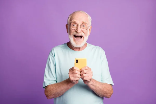 Canlı menekşe renkli arka planda izole edilmiş iki elle telefonu tutan heyecanlı bir adamın fotoğrafı. — Stok fotoğraf