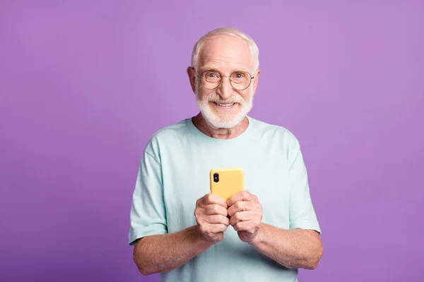 Canlı menekşe renkli arka planda izole edilmiş iki elle telefonu tutan yaşlı adamın fotoğrafı. — Stok fotoğraf