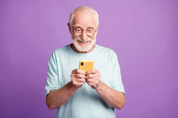 Mor renkli arka planda izole edilmiş iki elle telefonu tutan nişanlı yaşlı bir adamın fotoğrafı. — Stok fotoğraf