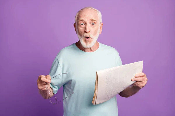 Retrato de encantador hombre viejo impresionado leyendo digest revista de noticias fresco mantenga gafas boca abierta aislado sobre violar el fondo — Foto de Stock