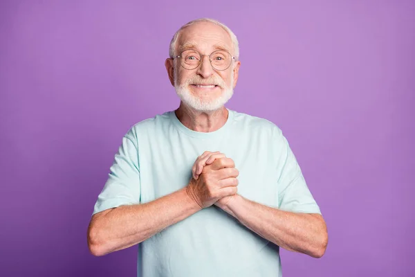 紫色の背景に隔離されたライトブルーのTシャツを手に持っている面白い歳のひげ男の写真 — ストック写真