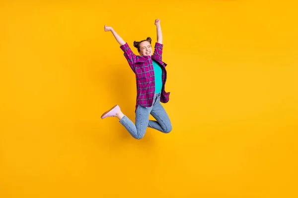 Full length photo of attractive crazy teen lady jump high up air flight ecstatic champion marathon sports competition wear casual plaid shirt shoes jeans isolated yellow color background — Stock Photo, Image