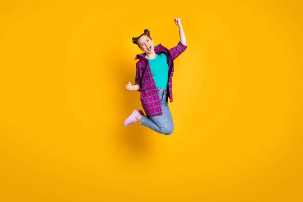 Foto de perfil em tamanho completo de muito louco animado adolescente senhora saltar bom humor competição ganhar levantar punhos usar casual xadrez camisa tênis jeans sapatos isolados cor amarela fundo — Fotografia de Stock