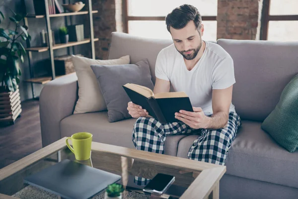 Portret van hem hij mooie aantrekkelijke gerichte bebaarde man zitten op divan lezen interessant boek besteden weekend vrije tijd op moderne loft industriële interieur stijl binnen — Stockfoto