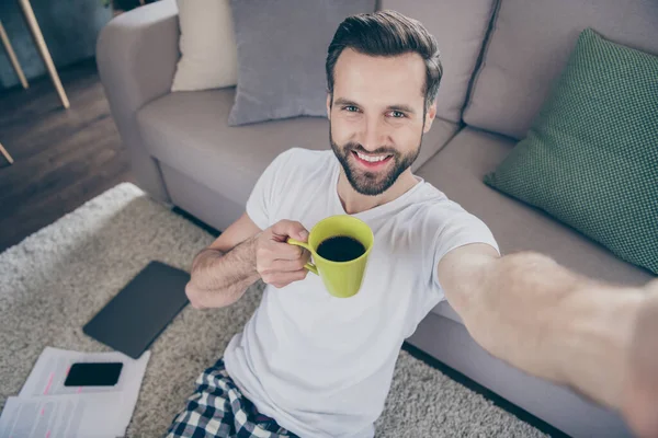 Primeros planos foto de chico guapo divertido sentarse sofá trabajo mañana navegación portátil freelancer trabajo remoto casa cuarentena bebida café tomar selfies pijama sala de estar en el interior — Foto de Stock