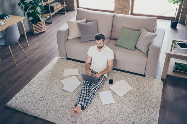 Arriba arriba de ángulo alto tamaño completo foto del vendedor enfocado hombre sentarse alfombra trabajo portátil remoto leer objetivo progreso proyecto usar ropa de dormir en casa en interiores — Foto de Stock