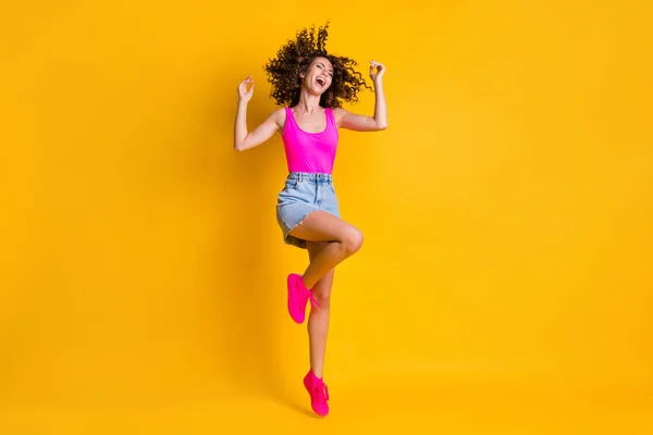 Full length photo of charming amazing curly lady jump up high students party happy wear pink tank top denim μίνι φούστα παπούτσια απομονωμένα έντονο φωτεινό κίτρινο χρώμα φόντο — Φωτογραφία Αρχείου