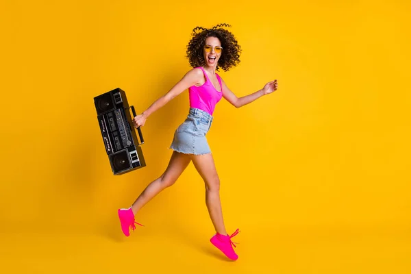 Πλήρης φωτογραφία προφίλ του σώματος του αστείο σγουρά hipster κυρία κρατήσει ρετρό boom box φοιτητές εκδήλωση διακοπές άλμα βόλτα παραλία φορούν ήλιο specs ροζ σλιπ denim παπούτσια φούστα απομονωμένο κίτρινο χρώμα φόντο — Φωτογραφία Αρχείου