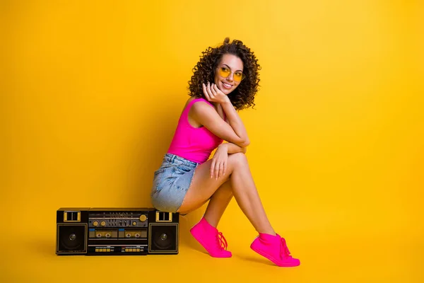 Full size profile photo of funny wavy hipster dj lady sitting side boom box holiday party look empty space wear sun specs pink singlet denim skirt shoes isolated shine yellow color background — Stock Photo, Image
