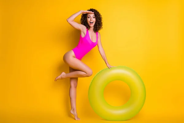 Full length photo of pretty funny tourist lady swim big green round float circle look distant wondered ship cruise landscapes wear pink swimsuit isolated vivid yellow color background — Stock Photo, Image