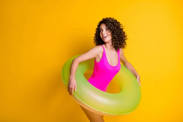 Foto retrato de menina no desgaste de natação rosa olhando para o espaço em branco segurando anel inflável verde isolado no fundo colorido amarelo brilhante — Fotografia de Stock