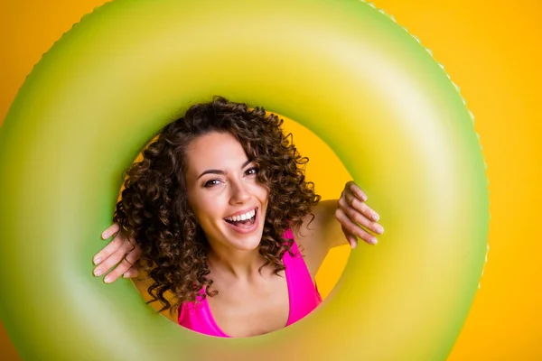 Foto portret van vrouw op zoek door opblaasbare groene ring met roze zwemkleding geïsoleerd op felgele achtergrond — Stockfoto