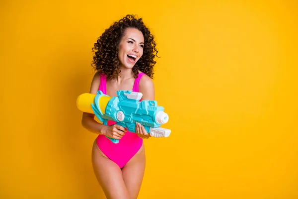 Foto retrato de mulher segurando arma de água pronto para lutar rindo vestindo rosa nadar desgaste isolado no fundo de cor amarelo brilhante — Fotografia de Stock
