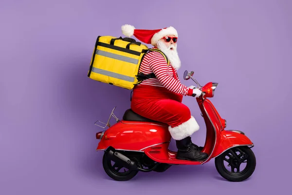 Foto van santa drive scooter fast food levering slijtage rugzak x-mas kostuum gestreepte shirt cap specs geïsoleerde paarse kleur achtergrond — Stockfoto