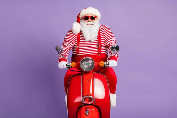 Zdjęcie starego Santa Claus jazdy motocykla nosić X-mas kostium w paski koszula okulary odizolowany fioletowy kolor tła — Zdjęcie stockowe