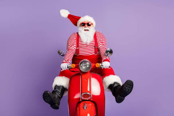 Foto van funky santa claus zorgeloos rijden scooter dragen x-mas kostuum gestreepte shirt cap brillen geïsoleerde paarse kleur achtergrond — Stockfoto