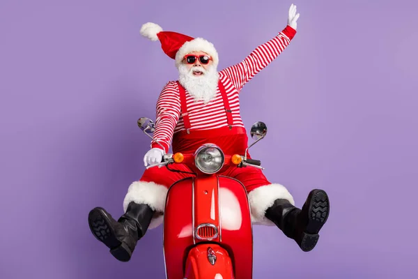Dertsiz Noel Baba 'nın resmi. Bisiklet sürme, retro-noel kostüm, çizgili başlık, güneş gözlüğü, izole edilmiş mor renk arka plan. — Stok fotoğraf