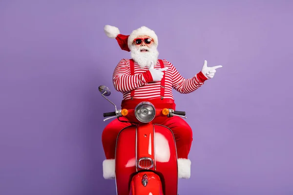 Photo of excited santa drive moped indicate finger empty space wear x-mas costume isolated violet color background