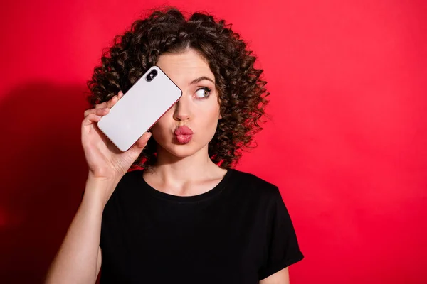 Portré fiatal nő fedél szem mobiltelefon smartphone csók ajkak elszigetelt piros szín háttér — Stock Fotó