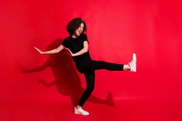 Photo portrait full body view of girl kicking raising leg dancing isolated on vivid red colored background — Stock Photo, Image