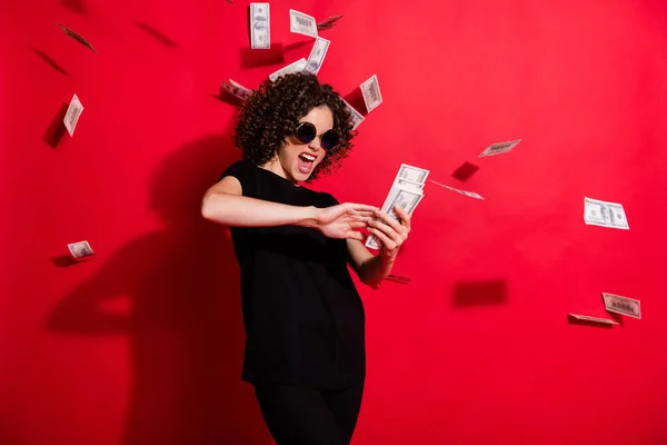 Foto portrét šílené dívky házet peníze ve vzduchu izolované na živém červeném pozadí — Stock fotografie
