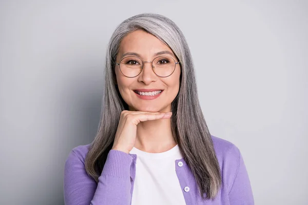 Foto av härlig söt pensionär dam arm haka toothy strålande glänsande leende tandläkare bära glasögon glasögon vit skjorta violett kofta isolerad grå färg bakgrund — Stockfoto