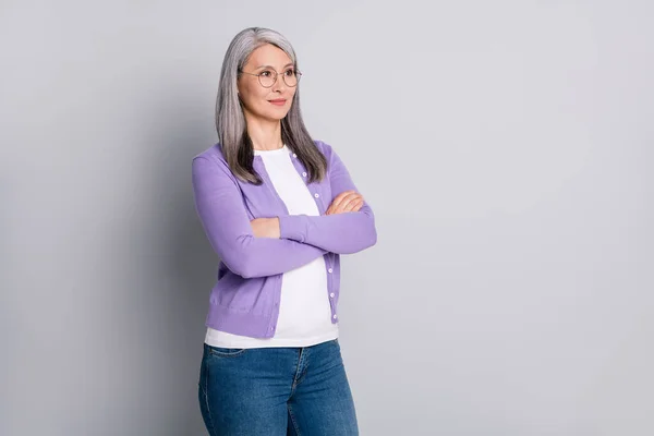 Profile photo of cute pretty mature lady folded arms self-assured look empty space wear glasses white shirt violet cardigan denim jeans isolated grey color background — Stock Photo, Image