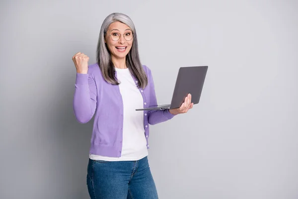 La fortuna está de mi lado hoy. Retrato fotográfico de la divertida secretaria mayor sonriendo alegremente riéndose sintiéndose feliz sosteniendo la computadora portátil escribiendo correos electrónicos aislados sobre un fondo de color gris —  Fotos de Stock