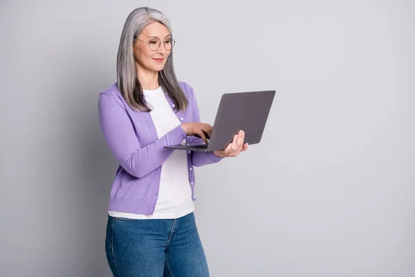 Portrait photo d'une femme d'affaires âgée souriante et confiante portant des lunettes travaillant avec un ordinateur portable moderne lisant la recherche sur Internet isolé sur fond de couleur grise — Photo