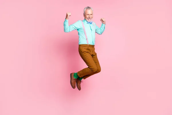 Longitud completa tamaño del cuerpo perfil lateral foto del anciano sonriente saltando alto usando ropa retro aislado sobre fondo de color rosa —  Fotos de Stock