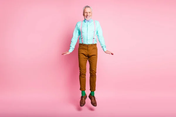 Tam boy beden ölçülerinde mutlu gülümseyen yaşlı bir adamın pembe arka planda tek başına atlayan pantolon askısı takan bir gülüşünün fotoğrafı. — Stok fotoğraf