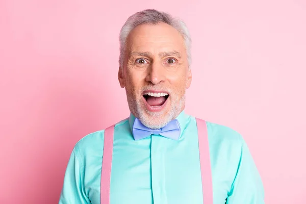 Фотографічний портрет шокованого здивованого літнього чоловіка, який одягнений в бантик, посміхається з відкритим ротом ізольовано на рожевому кольоровому фоні — стокове фото