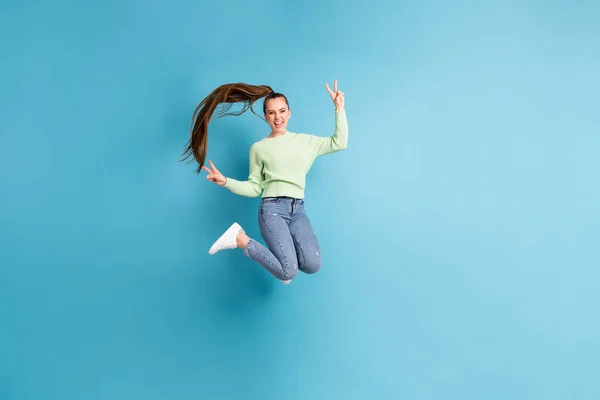 Plná délka tělo velikost fotografie skákající dívka s dlouhými vlasy ukazující V-sign obě ruce izolované na živém modrém pozadí — Stock fotografie
