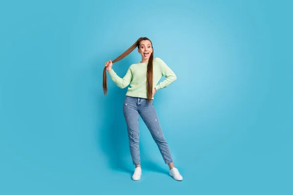 Portrait photo de fille montrant la langue tenant les cheveux isolés sur fond bleu pastel — Photo