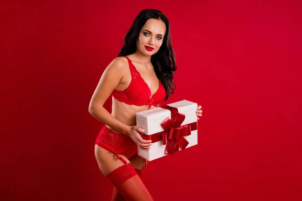 Foto de sexy encantadora mujer de pelo castaño calma llevar caja de regalo ropa interior aislada en el fondo de color rojo —  Fotos de Stock