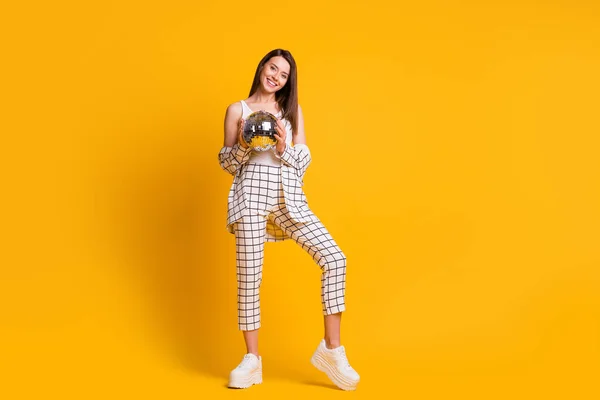 Πλήρες μέγεθος φωτογραφία του χαμογελαστού γοητευτικό κορίτσι καστανά μαλλιά κατέχουν ντίσκο μπάλα φορούν κοστούμι λευκό tank-top sneakers απομονώνονται σε κίτρινο φόντο — Φωτογραφία Αρχείου