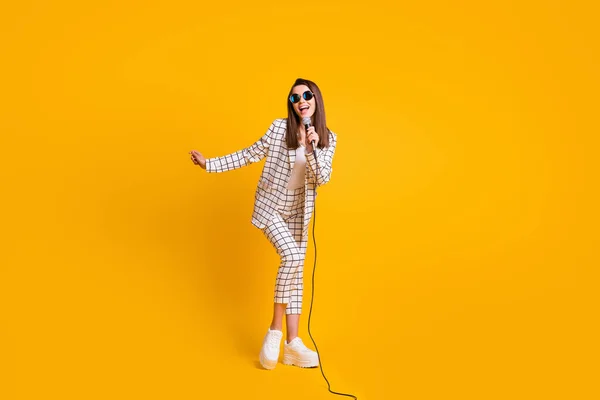 Teljes hossz testméret fotó lány teljesítő mikrofon fesztivál színpadon visel napszemüveget elszigetelt élénk sárga színű háttér — Stock Fotó