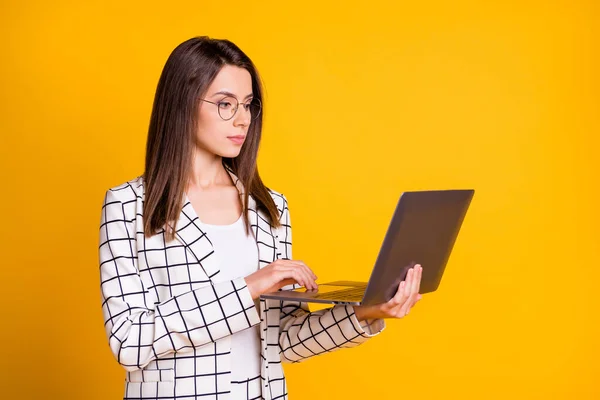 Foto ritratto di donna concentrata che lavora al computer indossando occhiali tuta isolata su vibrante sfondo di colore giallo — Foto Stock
