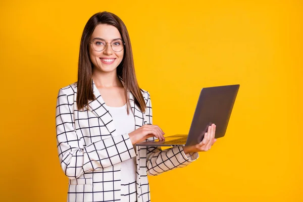 Foto porträtt av vacker kvinna att hålla bärbar dator bär glasögon ler isolerad på ljus gul färg bakgrund — Stockfoto